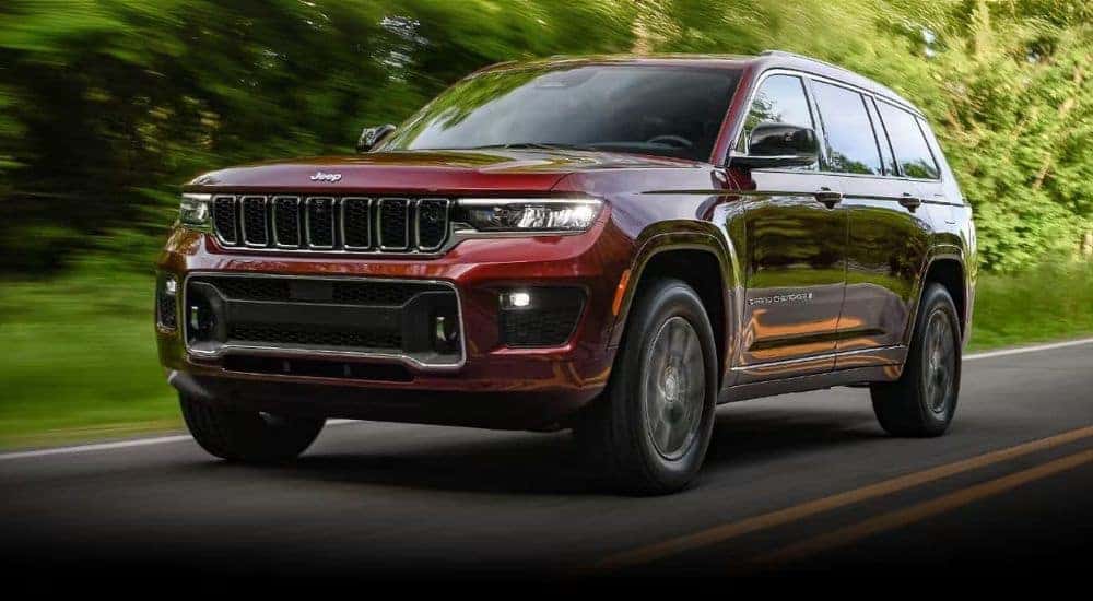 Maroon 2023 Jeep Grand Cherokee driving to a used car dealer