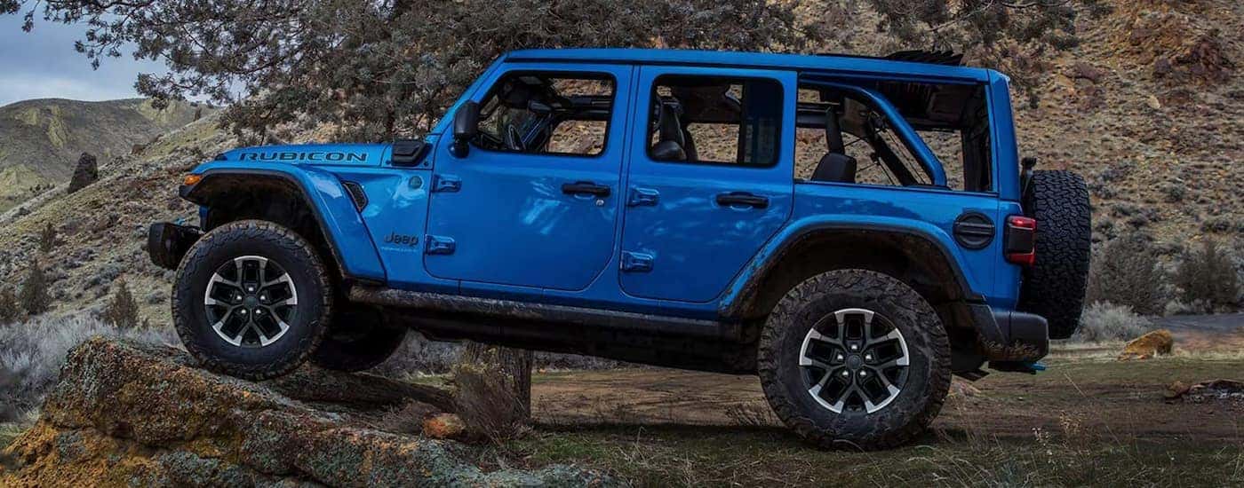 Blue 2025 Jeep Wrangler off-roading on a trail