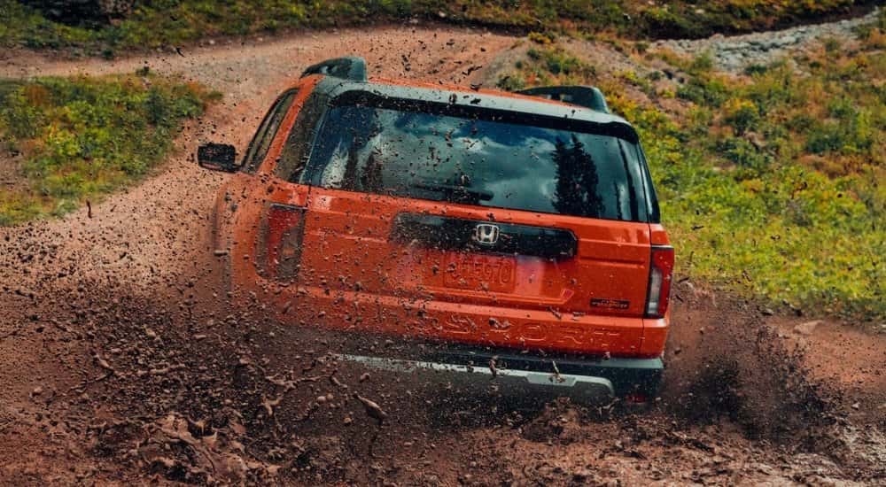 Orange 2026 Honda Passport TrailSport Elite driving to a Honda dealer