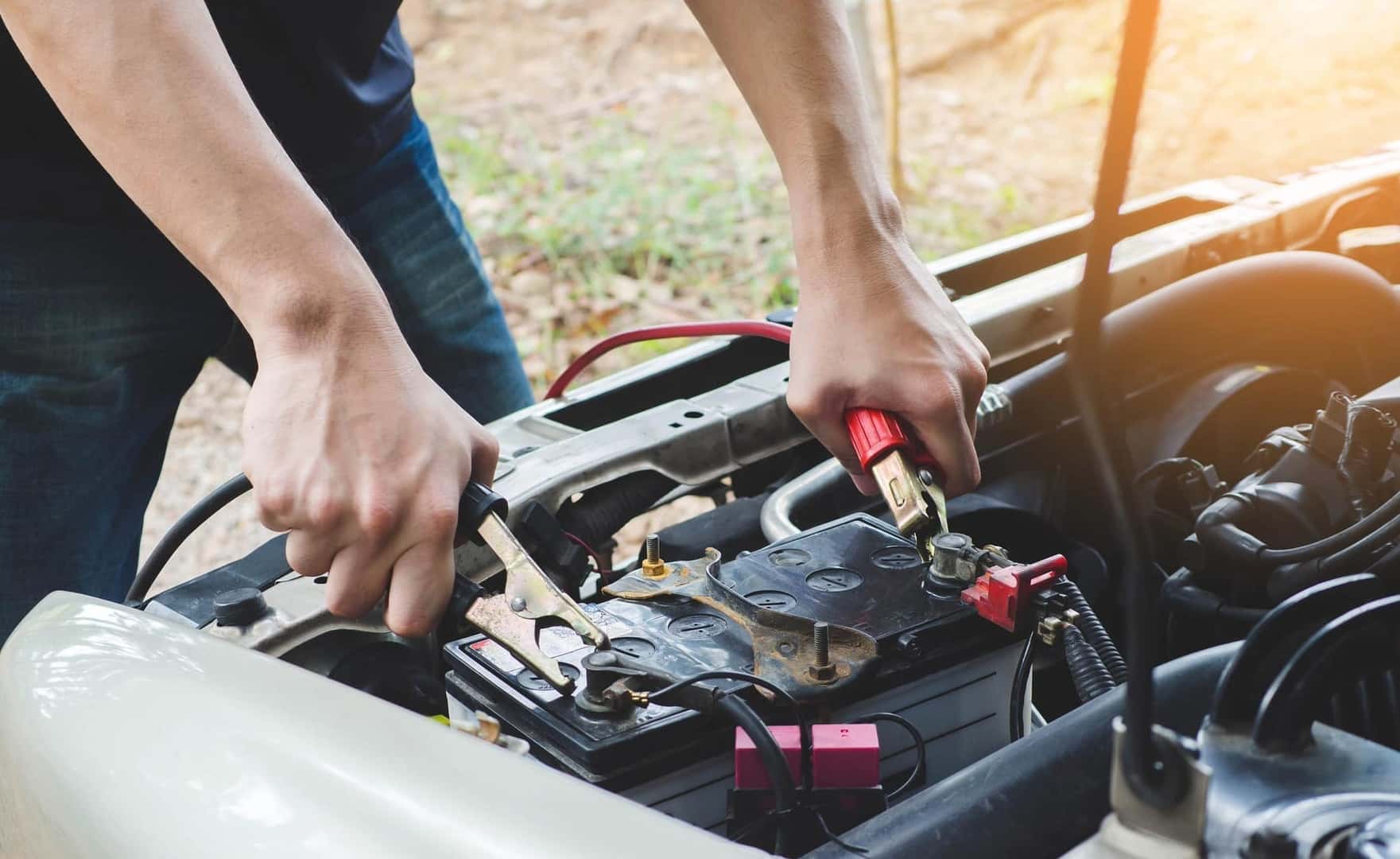 Man connecting jumper cables to a car battery