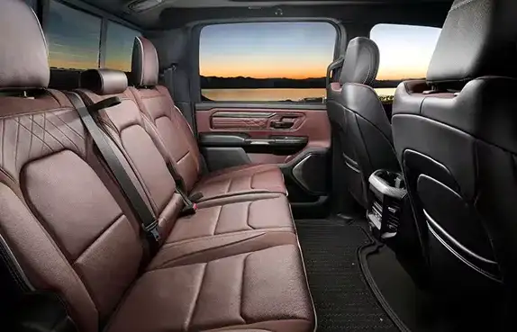 Rear seats of the 2027 Ram 1500 in brown leather with a sunset through the rear window