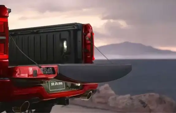 Lowered tailgate of a red 2027 Ram 1500 at dusk