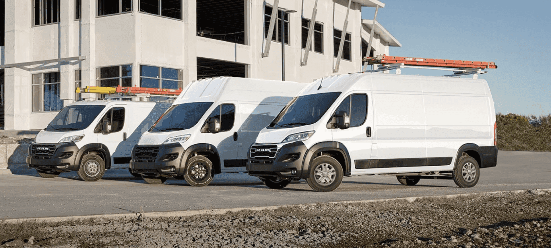 Ram ProMaster cargo vans with ladder racks parked at a construction site, part of the Ram truck lease lineup at Sierra CDJR of Monrovia
