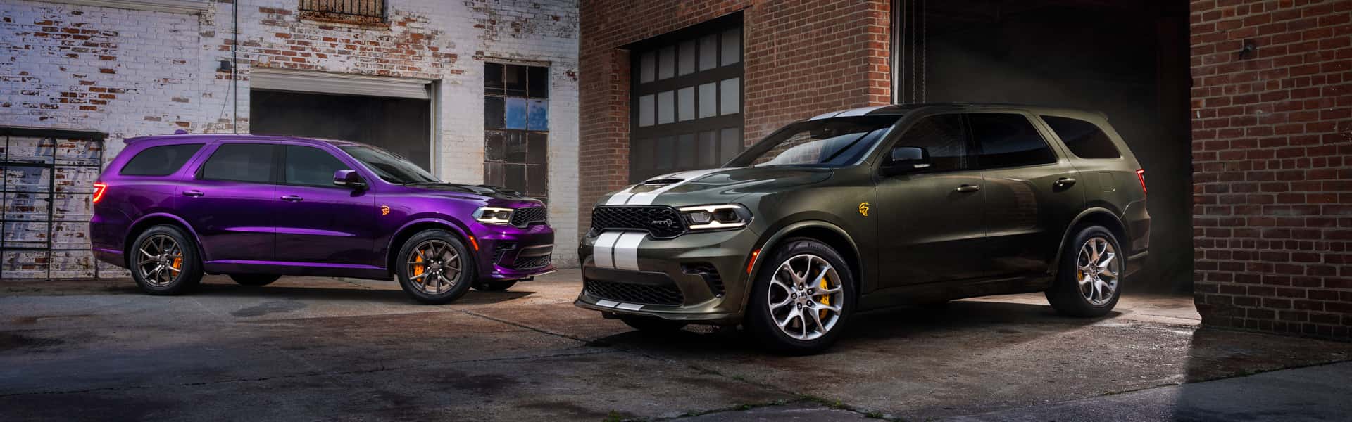 2026 Durango SRT Hellcat Jailbreak in Stryker Purple and in Green Machine parked in an alleyway behind buildings on a cloudy day.