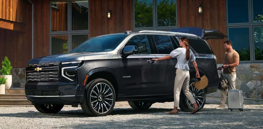 Two people loading luggage into a gray 2026 Chevrolet Tahoe SUV