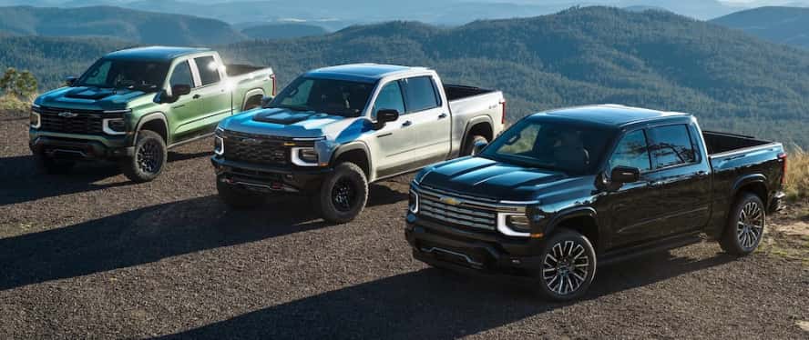 3 Chevrolet Silverado trucks parked on a mountain ledge