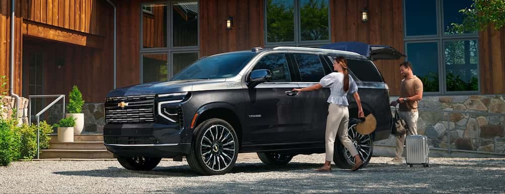 A couple loading luggage into a black 2026 Chevrolet Tahoe SUV