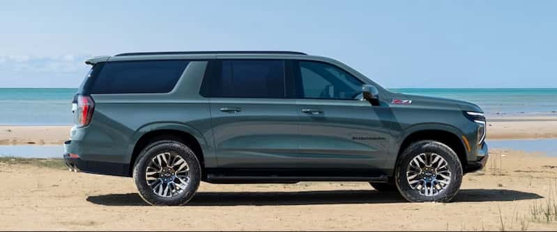 A side view of a 2026 Chevrolet Suburban SUV parked on a beach