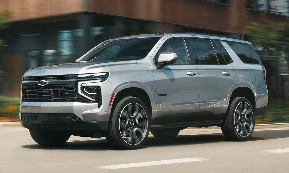 A silver 2026 Chevrolet Tahoe SUV driving down a city street