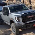 2026 GMC Sierra HD driving uphill while towing a large cargo