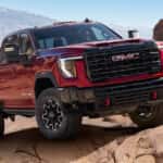 2026 GMC Sierra 2500 driving on a rocky desert trail with rugged mountains