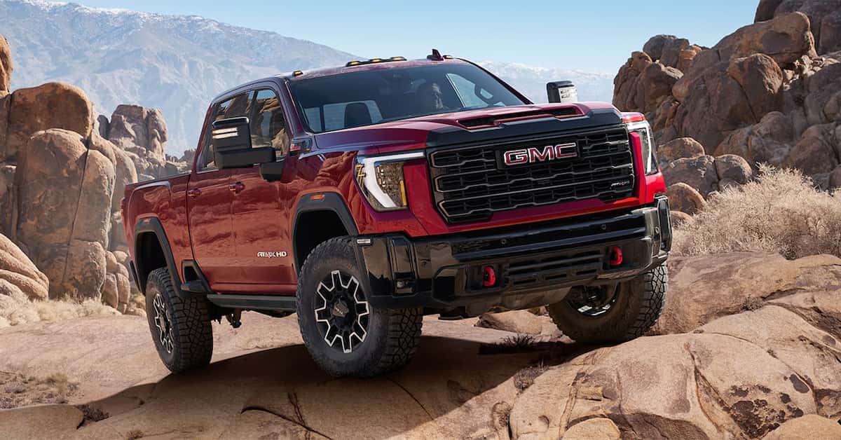 2026 GMC Sierra 2500 driving on a rocky desert trail with rugged mountains