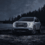 GMC SUV parked by a lake at night