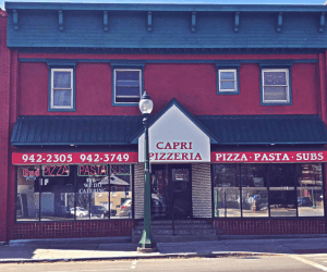 Exterior of Capri Pizzeria in Boonville, NY. Red building, with green awning