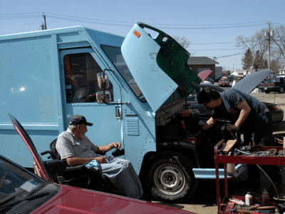 Rich Nimey in a wheelchair supervising the repair of a truck
