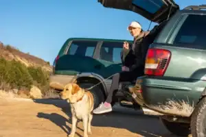 Girl sitting in back of Jeep with a dog