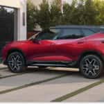 Rear three-quarter view of a red 2026 Chevrolet Blazer with a black roof parked in a residential driveway.