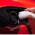 Close-up of a person charging a red 2026 Chevrolet Blazer EV at its open charging port.