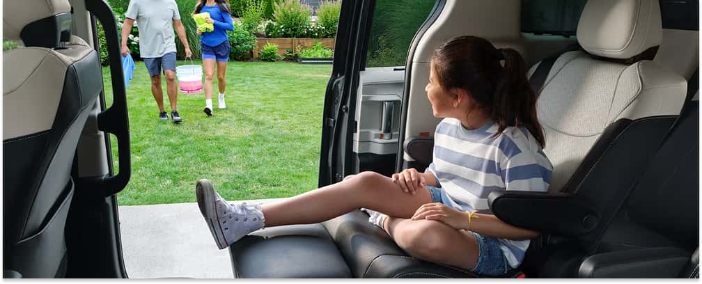 Rear captain's chair with an extended leg rest inside the 2026 Toyota Sienna with the sliding door open.