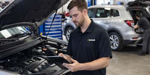 Service Tech Working on Vehicle holding an iPad