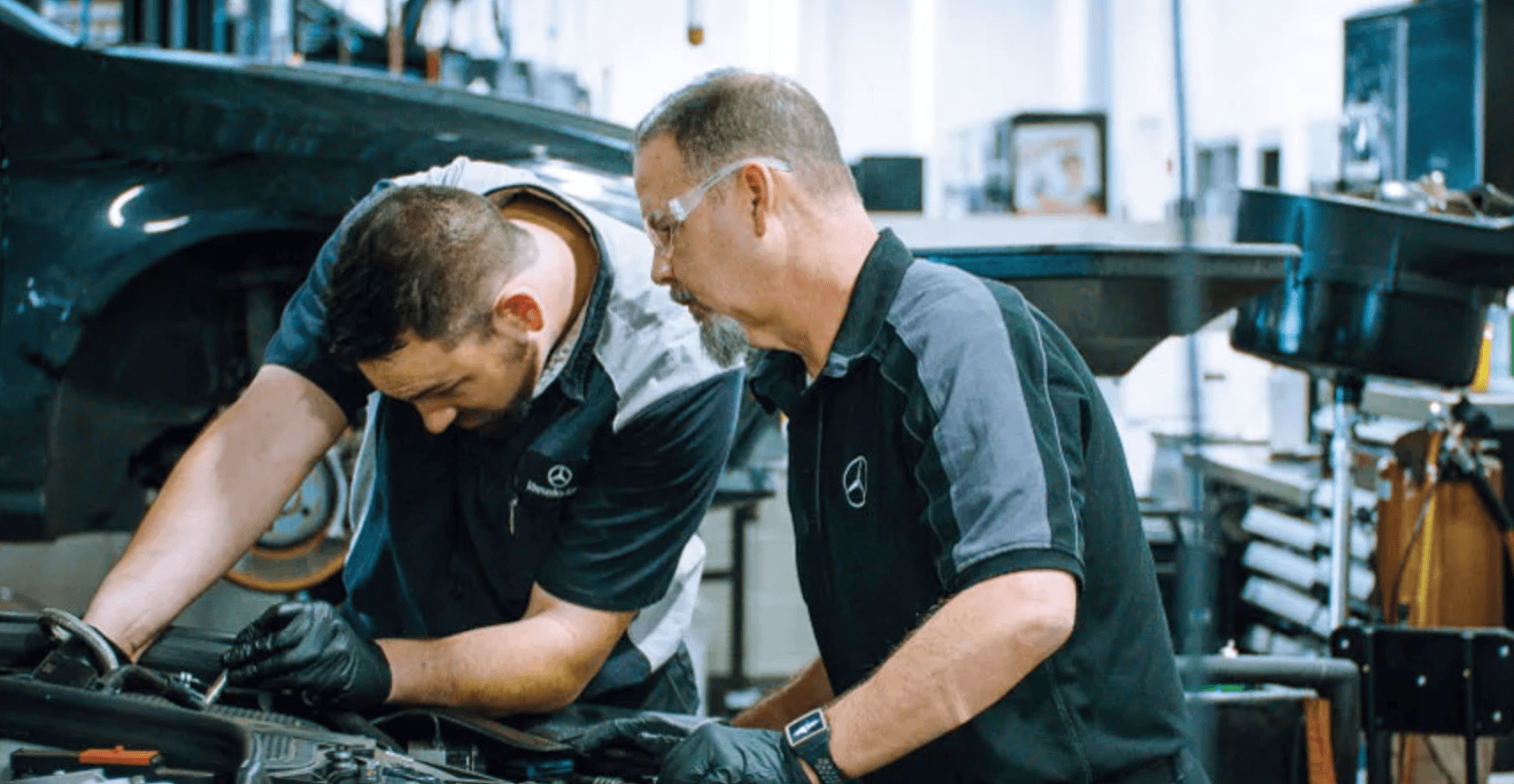 Two Mercedes-Benz service technicians working on a vehicle