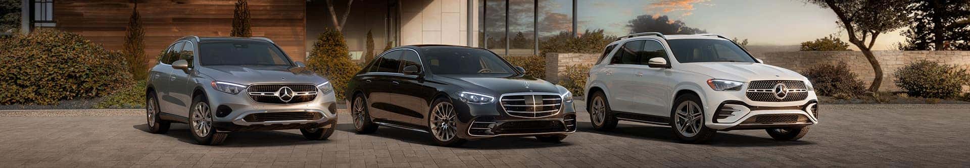 Three Mercedes Benz vehicles parked in front of an upscale home