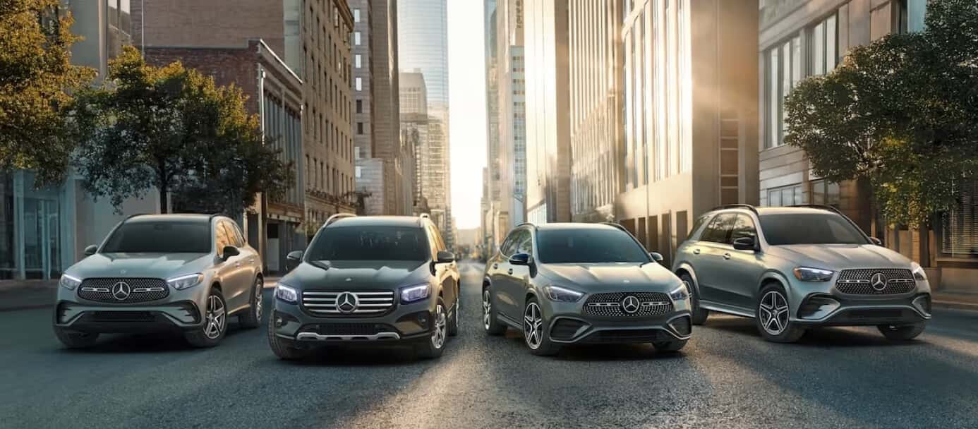 Several 2026 Mercedes-Benz SUV models parked side-by-side on a shady city street.