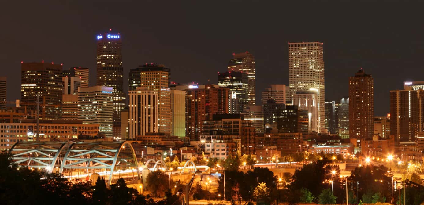 Wide angle view of the Denver skyline lit up at night.