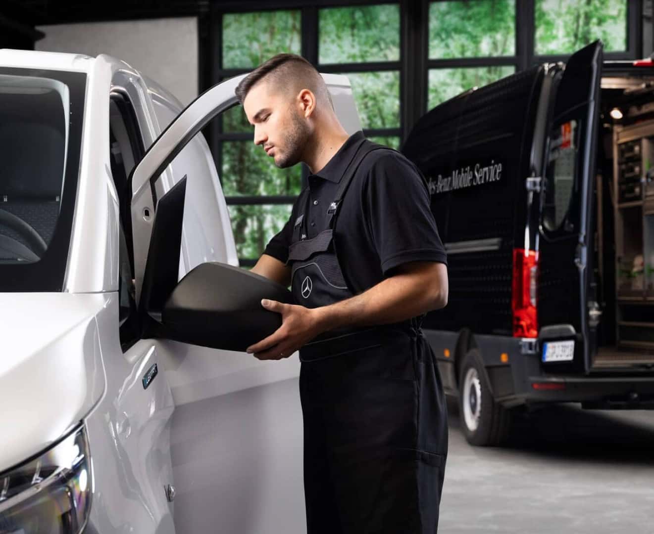 A Mercedes-Benz Mobile Service Technician adjusts the mirrors on a Mercedes van in a brightly lit parking zone.