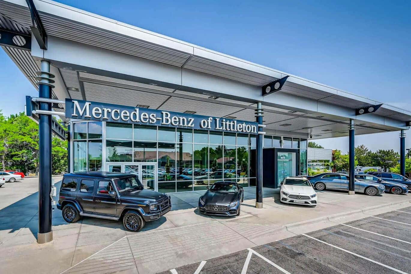 Exterior street view of Mercedes-Benz of Littleton with several Mercedes vehicles parked out front on a sunny day.