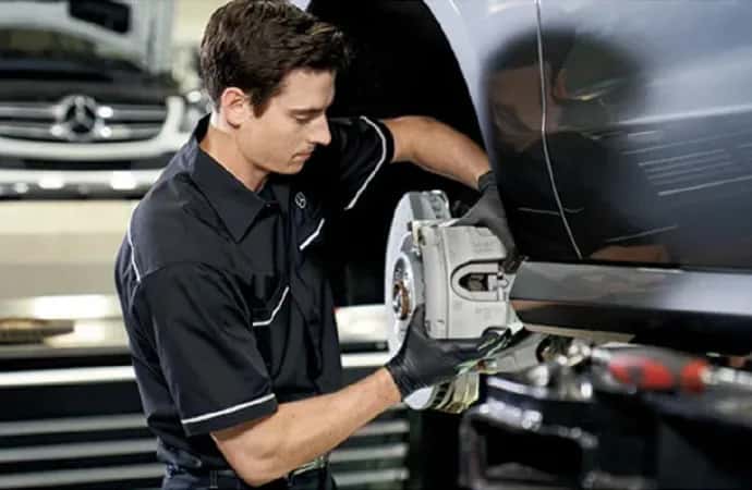 Certified technician verifying safety systems, brake pad thickness, and tire tread depth