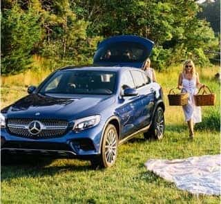 Family setting up a picnic next to a Mercedes-Benz vehicle