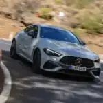 2025 White Mercedes AMG CLE Coupe front view driving around a curveon a road