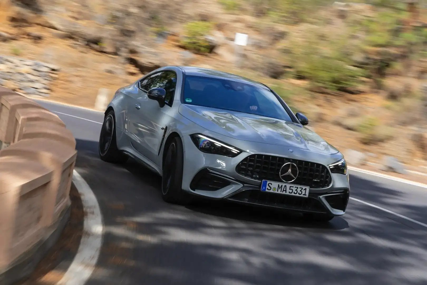 2025 White Mercedes AMG CLE Coupe front view driving around a curveon a road 