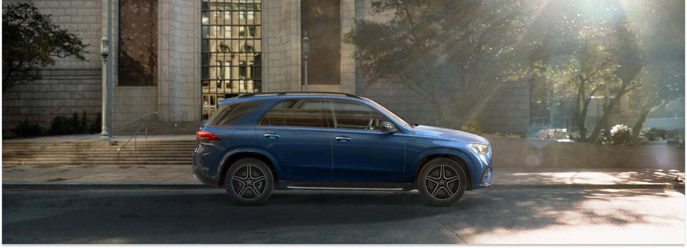 Side profile of a blue 2026 Mercedes-Benz GLE SUV parked on a city street.