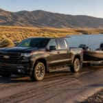 2026 Chevrolet Silverado 1500 towing a boat trailer at a Nevada lake ramp with Carson Range mountains in the background