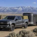 2026 Chevrolet Silverado 1500 hauling fence posts in the bed and towing a stock trailer on a Nevada ranch road near Carson City
