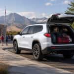 2027 GMC Acadia with rear liftgate open, sports gear and backpacks loaded, Carson Range in background