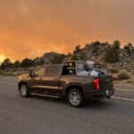 2026 GMC Sierra 1500 loaded with emergency evacuation supplies on a Nevada highway under a wildfire smoke sky