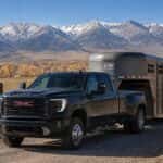 2026 GMC Sierra 3500 HD Crew Cab pulling a gooseneck livestock trailer through Carson Valley, Nevada with the Sierra Nevada mountains in the background