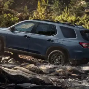 2026 Honda Pilot TrailSport Smoke Blue Pearl driving over rocks