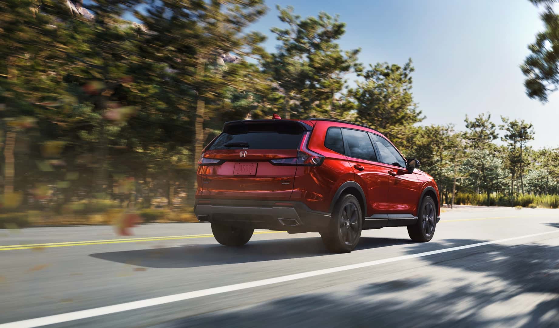 The Well-Engineered Back Exterior Of The Fuel-Efficient 2026 Honda CR-V Sport Touring Hybrid, Driving On The Road Past Blurred Trees