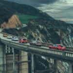 A Long Bridge With All The Compared Cars From The Car And Driver Comparison Review, Driving Under A Stormy Sky