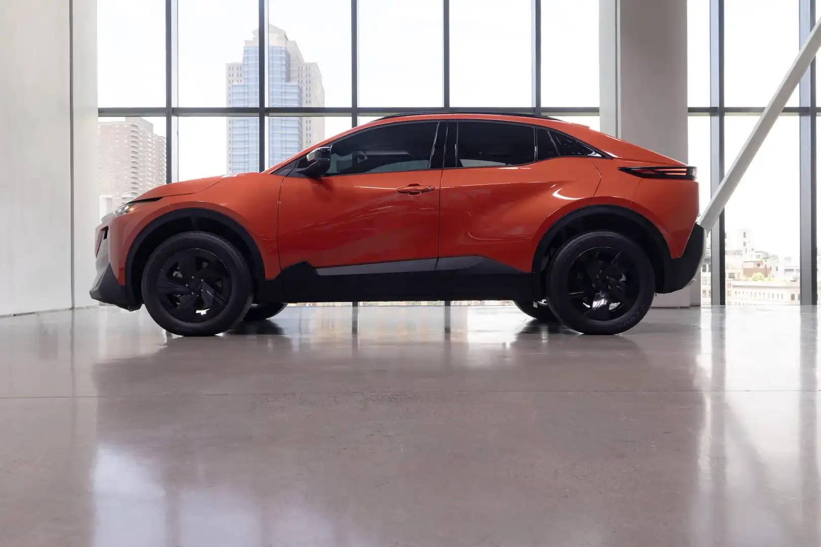Orange Subaru Uncharted parked in a showroom side profile