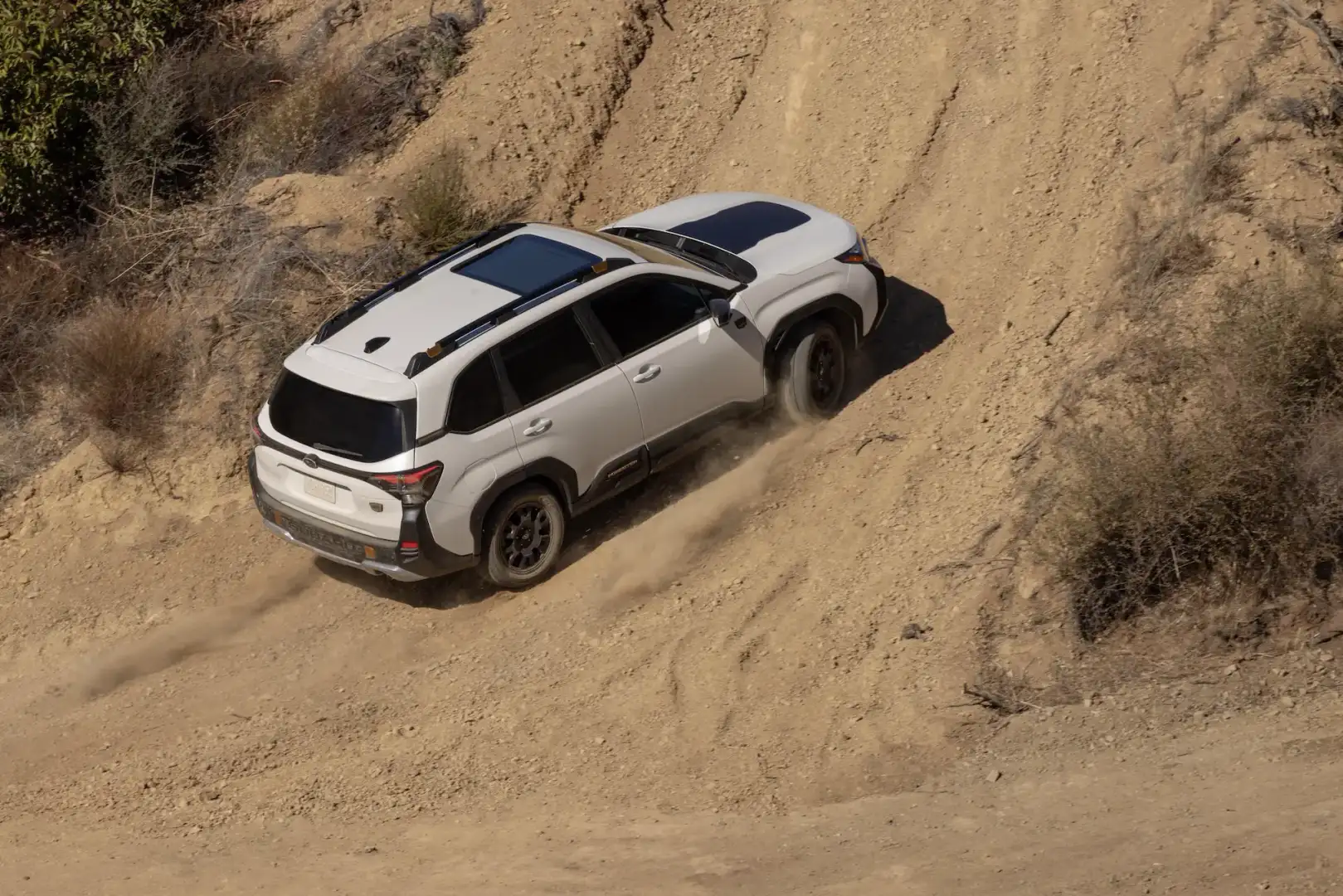 White 2026 Subaru Forester off roading up a sand dune hill