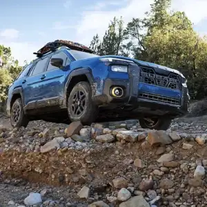 2026 Subaru Outback Wilderness Geyser Blue driving over rocks