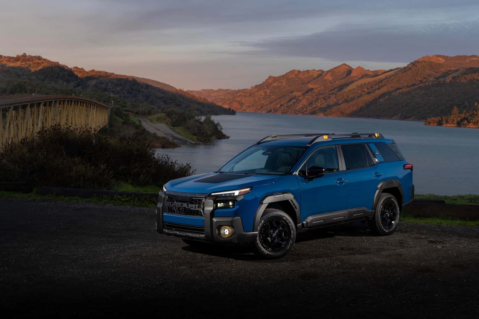 The Commanding 2026 Subaru Outback Wilderness, Parked On A Cliff, In View Of A Beautiful Lake, Rugged Mountains, And A Dependable Bridge