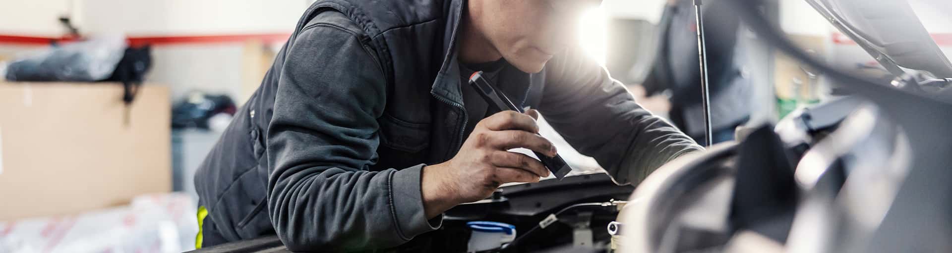A service technician under the hood of a vehicle in the service center.