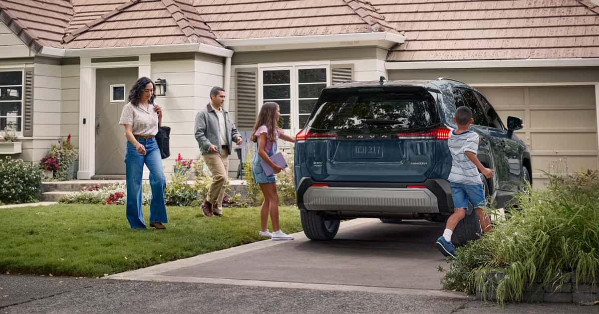 A family packing into their Toyota RAV4 parked in their driveway.