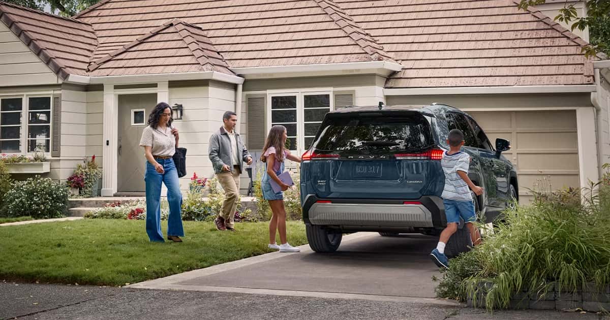 A family getting into their Toyota RAV4 parked in the driveway.